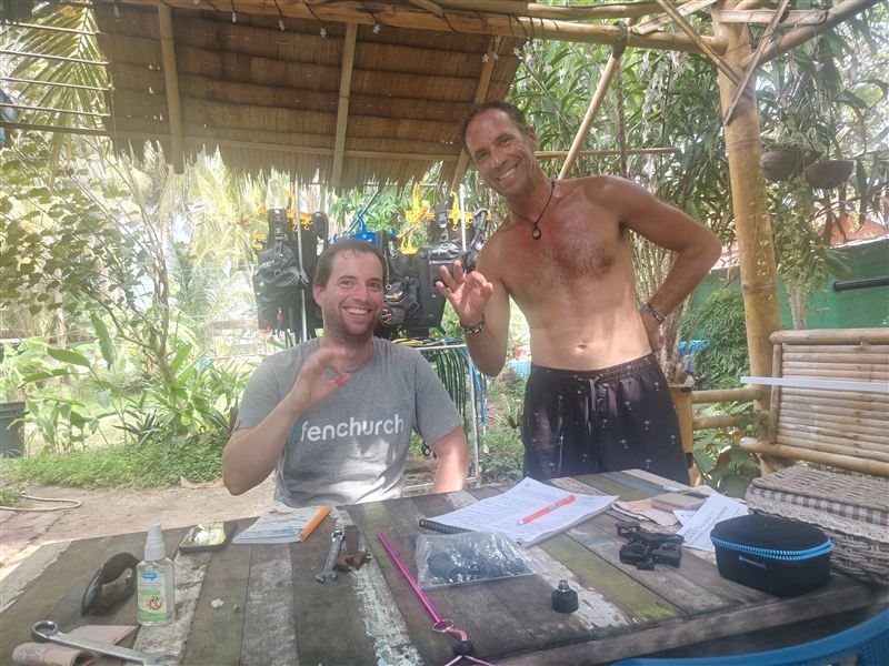 Un alumno de Advanced y su instructor sonriendo en una mesa del jardín después de repasar el examen.