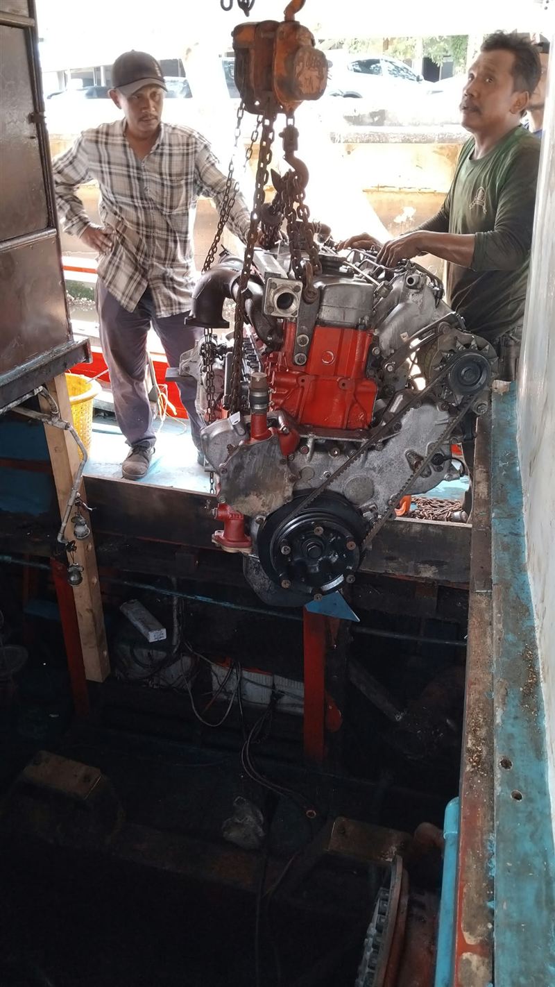 Two mechanics guiding the engine into the engine room.