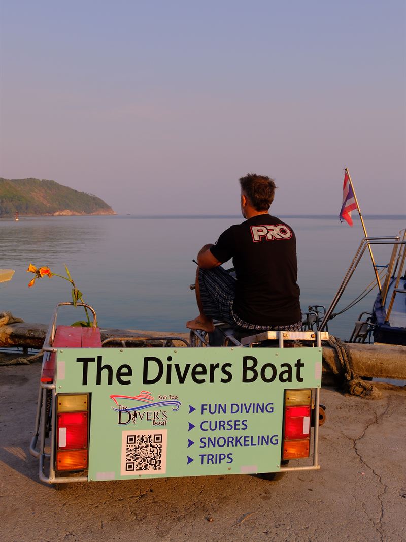 Boris, nuestro instructor principal, en el muelle de Chaloklum junto al cartel de The Divers Boat.