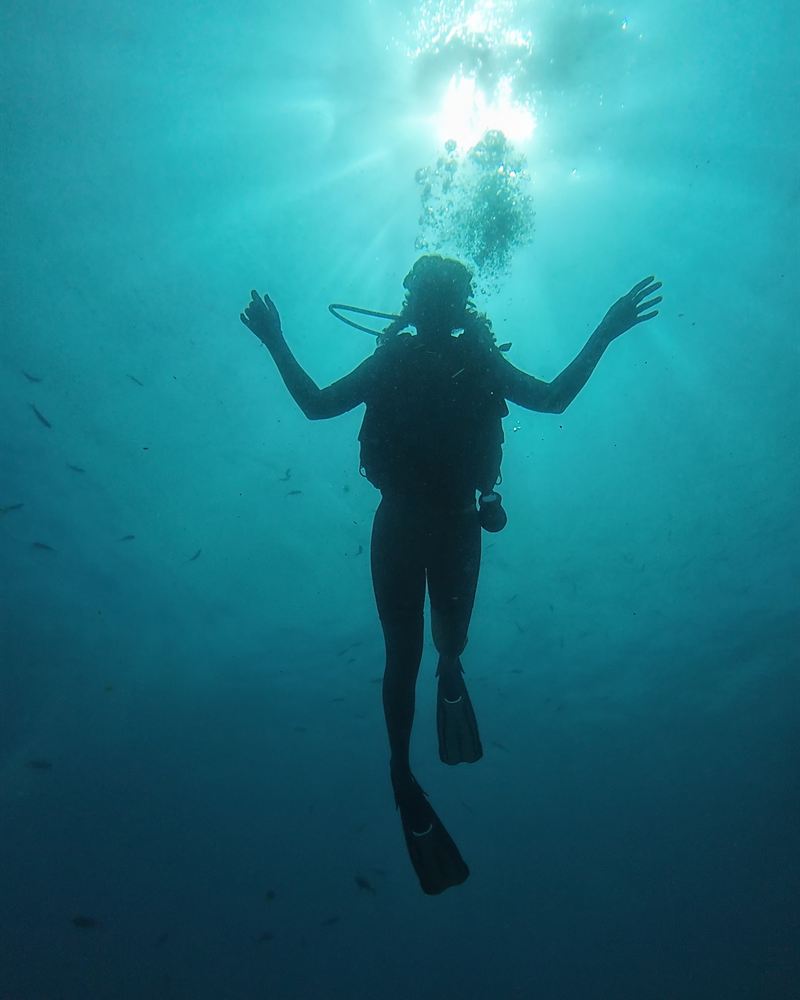 A diver silhouetted against the sun during a slow ascent.