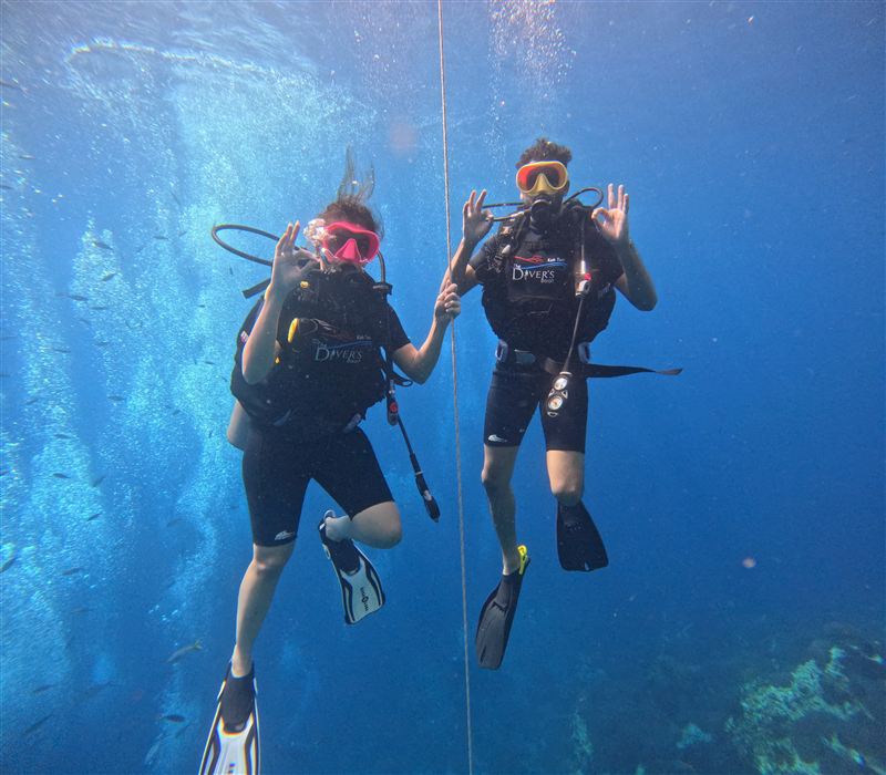 Dos alumnos de bautismo en el cabo de descenso, haciendo los dos la señal de OK.