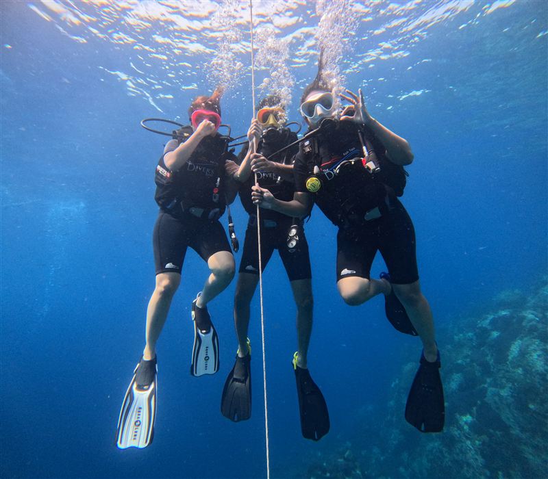Three Try Dive students holding the descent line together.