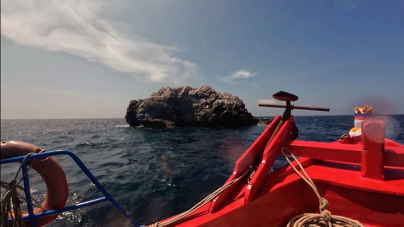 Sail Rock asomando del agua, visto por encima de la proa del barco.
