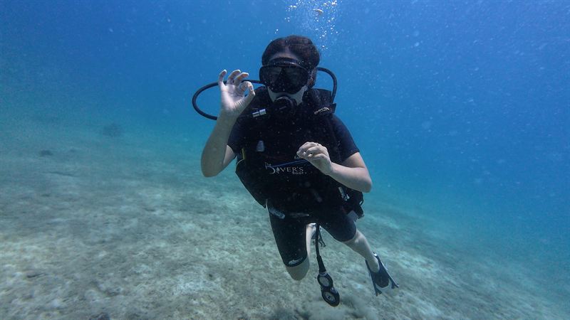 Un alumno de Open Water haciendo la señal de OK sobre la arena.