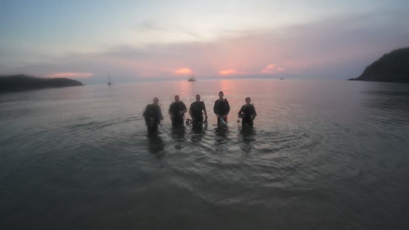 Un grupo de buceadores entrando en el mar al atardecer en Koh Phangan.